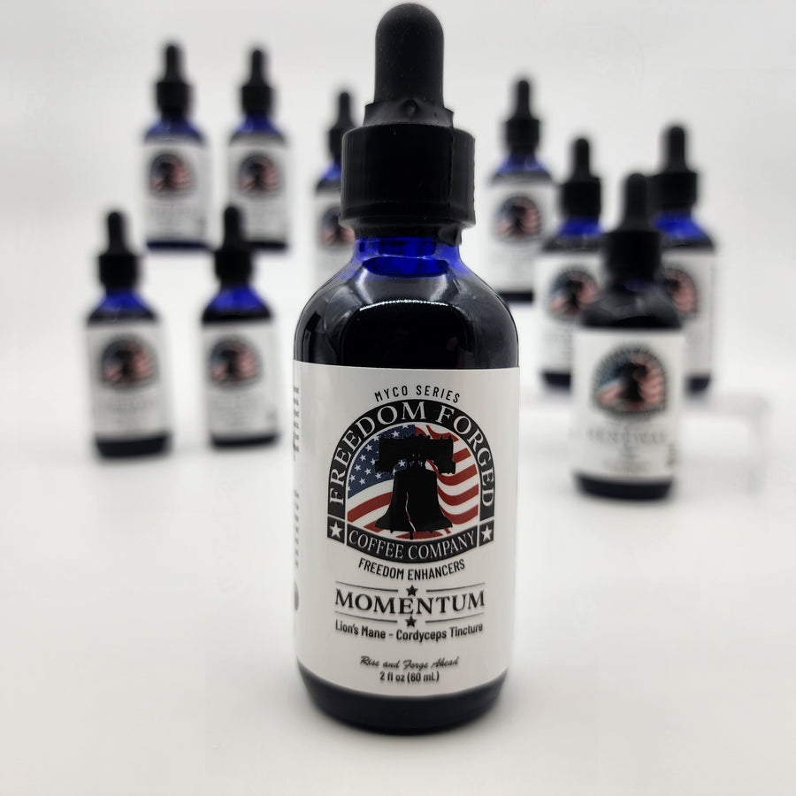 Bottle of Freedom Forged Coffee Company Momentum mushroom tincture on a white background with other similar bottles blurred in the background.