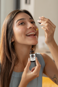 Female using dropper to place Momentum Lion's Mane and Cordyceps tincture under her tongue. 